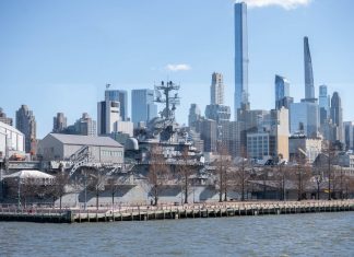 USS Intrepid museum ship with NYC skyscrapers in the background.