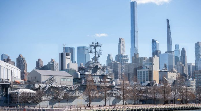 USS Intrepid museum ship with NYC skyscrapers in the background.