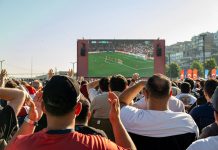 Crowd watching a soccer game on a large screen outdoors in Istanbul, Türkiye.