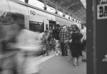 A black and white scene of commuters at a Lisbon train station, showcasing urban movement.