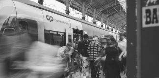 A black and white scene of commuters at a Lisbon train station, showcasing urban movement.