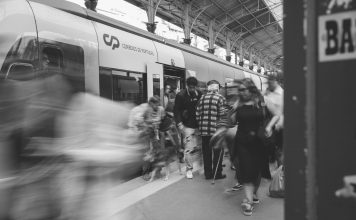 A black and white scene of commuters at a Lisbon train station, showcasing urban movement.