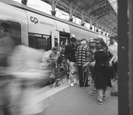 A black and white scene of commuters at a Lisbon train station, showcasing urban movement.