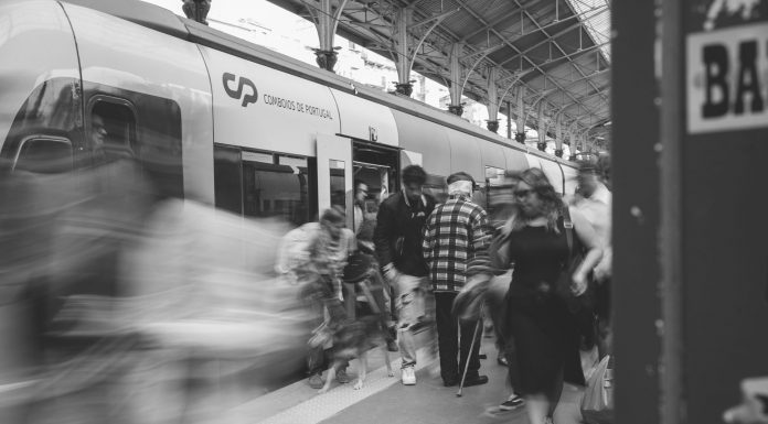 A black and white scene of commuters at a Lisbon train station, showcasing urban movement.