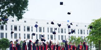A group of graduates in Vietnam celebrate by throwing caps into the air.