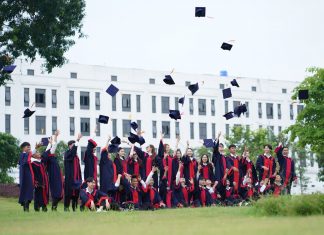 A group of graduates in Vietnam celebrate by throwing caps into the air.