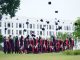 A group of graduates in Vietnam celebrate by throwing caps into the air.