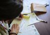 13,500 Jersey City Residents Face Loss of Medicaid or Food Benefits Under New Law A doctor fills out medical forms indoors, focusing on patient care and documentation.