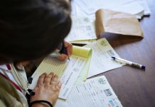 13,500 Jersey City Residents Face Loss of Medicaid or Food Benefits Under New Law A doctor fills out medical forms indoors, focusing on patient care and documentation.