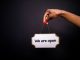 Close-up of a hand holding a 'We are open' sign against a black background.