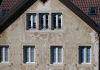 A Century in Jersey City, Now Fearing the End Close-up of an aged European house facade with multiple windows and rustic texture.