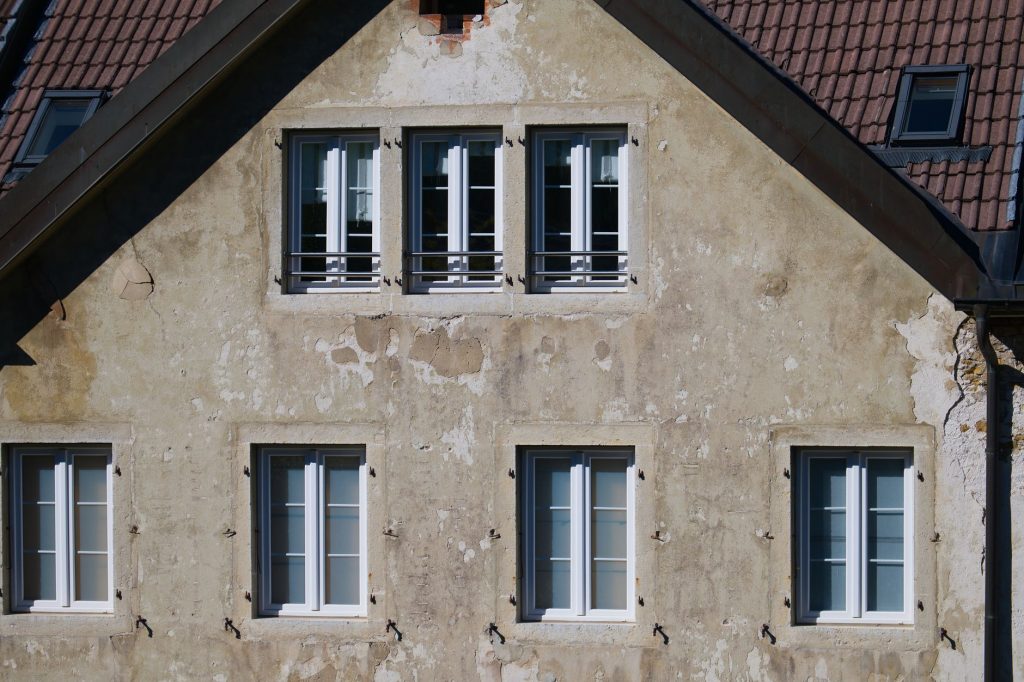 Close-up of an aged European house facade with multiple windows and rustic texture.