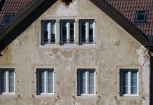 Close-up of an aged European house facade with multiple windows and rustic texture.