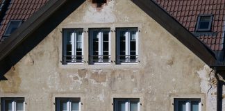 A Century in Jersey City, Now Fearing the End Close-up of an aged European house facade with multiple windows and rustic texture.