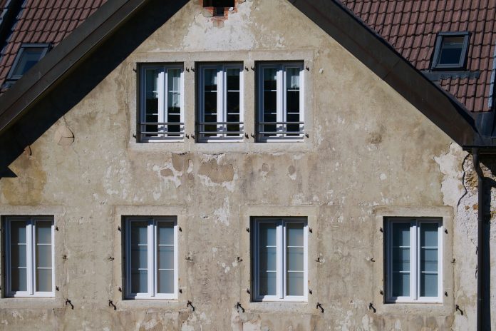 Close-up of an aged European house facade with multiple windows and rustic texture.