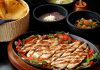 Tasty Mexican grilled chicken fajitas with colorful vegetables, tortillas, and sides, perfect for a savory meal.