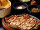 Tasty Mexican grilled chicken fajitas with colorful vegetables, tortillas, and sides, perfect for a savory meal.