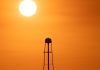 A striking sunset silhouette of a water tower against a vivid orange sky in Mather, CA.