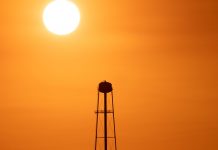 A striking sunset silhouette of a water tower against a vivid orange sky in Mather, CA.