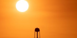 A striking sunset silhouette of a water tower against a vivid orange sky in Mather, CA.
