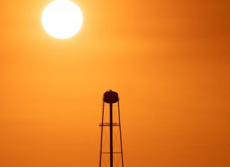 A Jersey City Heat Wave in Photos A striking sunset silhouette of a water tower against a vivid orange sky in Mather, CA.