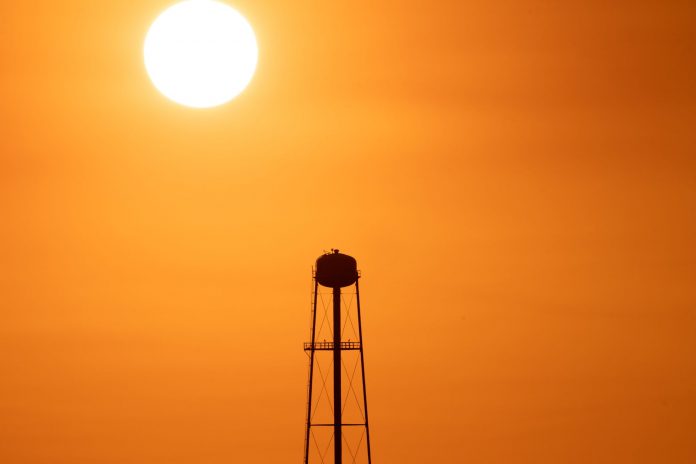 A striking sunset silhouette of a water tower against a vivid orange sky in Mather, CA.
