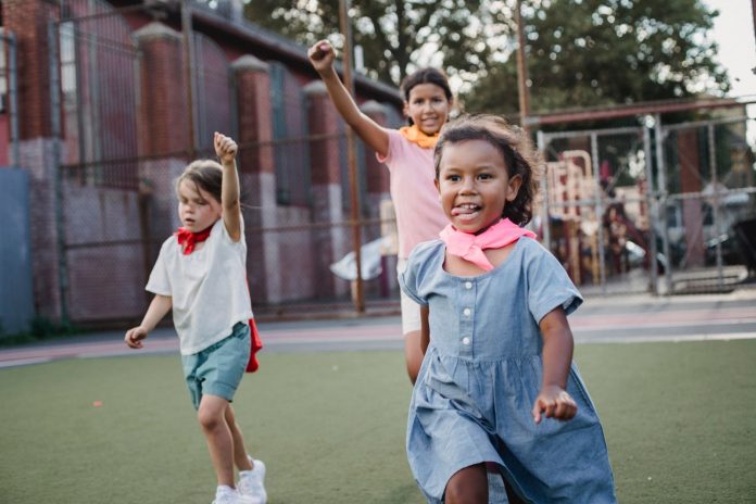 Three children enjoying a playful competition at an outdoor playground, showcasing motion and joy.