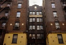 Low-angle view of urban brick apartment buildings with fire escapes, embodying classic city architecture.