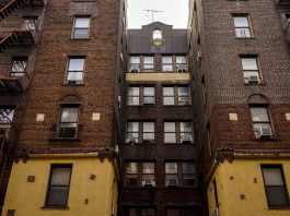 Low-angle view of urban brick apartment buildings with fire escapes, embodying classic city architecture.