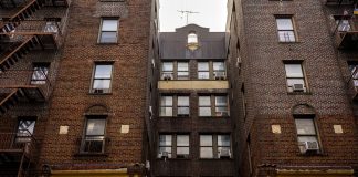 Low-angle view of urban brick apartment buildings with fire escapes, embodying classic city architecture.