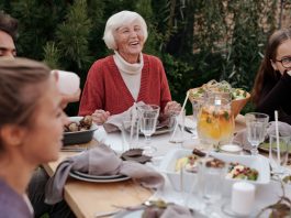 Bayonne hospital, city host first senior health event Smiling elderly woman with family and friends enjoying dinner at table backyard garden