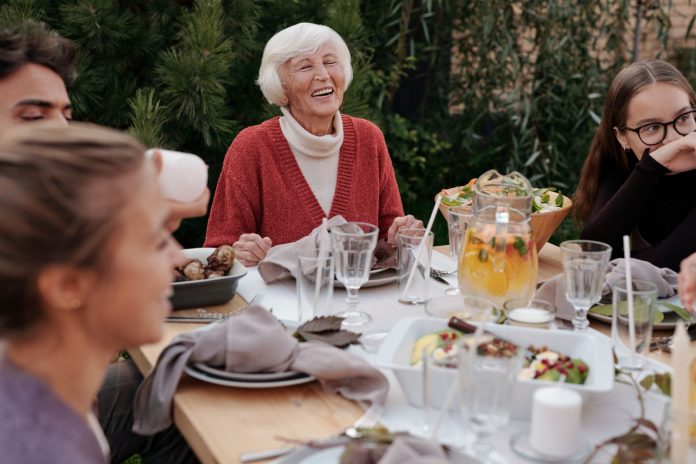 bayonne-hospital-city-host-first-senior-health-eve Smiling elderly woman with family and friends enjoying dinner at table backyard garden
