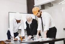 Bayonne Mayor Pledges Business-Focused Master Plan Update Group of architects discussing construction blueprints wearing hardhats in a modern office.