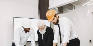 Bayonne Mayor Pledges Business-Focused Master Plan Update Group of architects discussing construction blueprints wearing hardhats in a modern office.