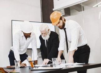 Bayonne Mayor Pledges Business-Focused Master Plan Update Group of architects discussing construction blueprints wearing hardhats in a modern office.