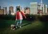 Best Activities for Kids in West New York (2026 Guide) Ethnic child with Yorkshire Terrier on leash preparing to run on meadow against urban skyscrapers