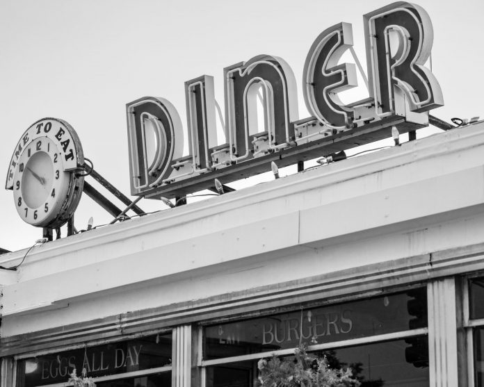 best-breakfast-spots-in-bayonne-2026 Black and white photo of a vintage diner sign with a clock in Somerville, MA.