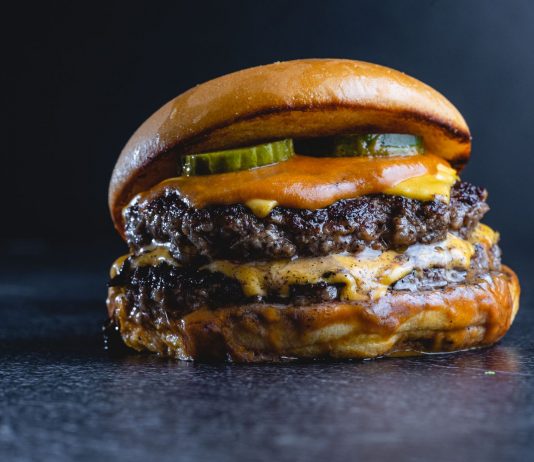 Mouth-watering beef cheeseburger with pickles, perfect for gourmet food photography.