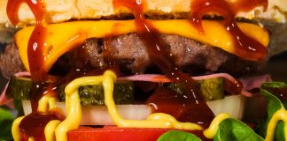 Mouth-watering close-up of a cheeseburger with toppings, showcasing textures and rich flavors.