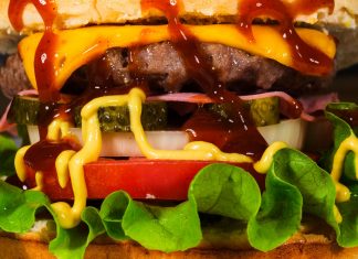 Mouth-watering close-up of a cheeseburger with toppings, showcasing textures and rich flavors.