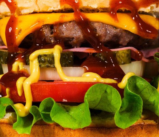Mouth-watering close-up of a cheeseburger with toppings, showcasing textures and rich flavors.