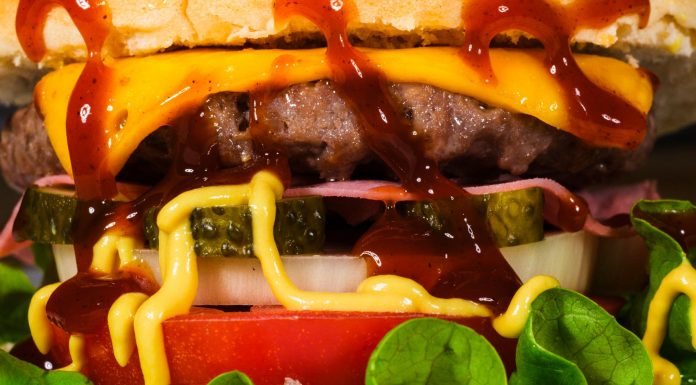 Mouth-watering close-up of a cheeseburger with toppings, showcasing textures and rich flavors.