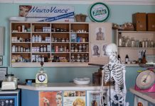 A nostalgic view inside an old-timey pharmacy featuring vintage medicine bottles and a medical skeleton on display.