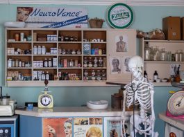 A nostalgic view inside an old-timey pharmacy featuring vintage medicine bottles and a medical skeleton on display.
