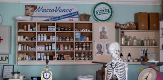 A nostalgic view inside an old-timey pharmacy featuring vintage medicine bottles and a medical skeleton on display.