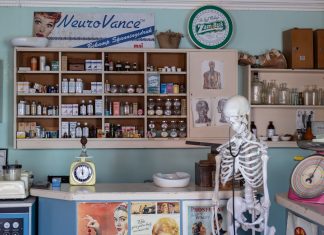 A nostalgic view inside an old-timey pharmacy featuring vintage medicine bottles and a medical skeleton on display.