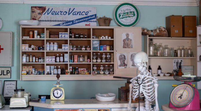 A nostalgic view inside an old-timey pharmacy featuring vintage medicine bottles and a medical skeleton on display.