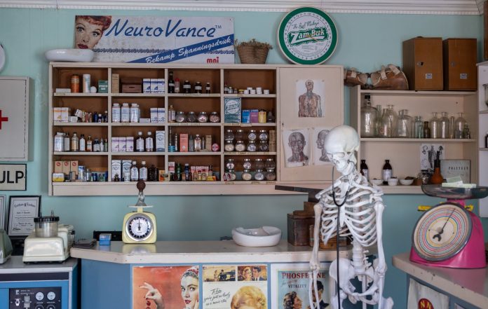 A nostalgic view inside an old-timey pharmacy featuring vintage medicine bottles and a medical skeleton on display.