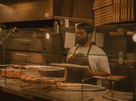 Pizza chef serving slices in a Milwaukee pizzeria, captured in warm tones.