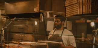Pizza chef serving slices in a Milwaukee pizzeria, captured in warm tones.